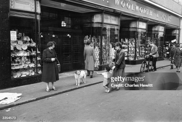 Passers-by in front of Woolworth's store in Brixton, south London. In the centre is Mrs Babs Sango, a British woman married to Johnnie Sango, a West...