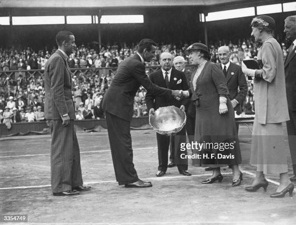 British tennis player Fred Perry shakes hands with Princess Helena Victoria on receiving the Davis Cup trophy for Great Britain, after his victory...