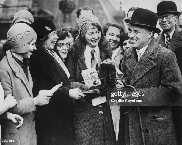 Charlie Chaplin signing autographs for the staff of the hotel where he is staying in London.