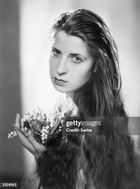 The long haired Frederique holding a bunch of lily-of-the-valley.