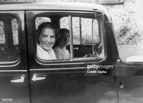 Diana Beaumont at the wheel of her car with fellow actress Ursula Hirst as a passenger. Both are appearing in 'Admirals All' at the Shaftesbury...