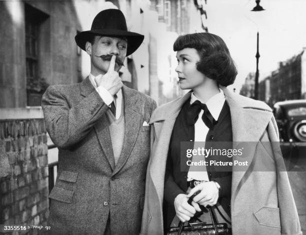 Irish actor Richard Todd fails to impress Jane Wyman with a false moustache during the filming of 'Stage Fright', directed by Alfred Hitchcock....