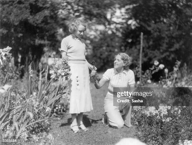 Diana Beaumont and Ursula Hirst picking flowers in the former's garden. Both are actresses appearing in 'Admirals All' at the Shaftesbury Theatre,...