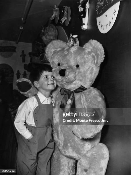 Six-year old Martin Stephens cuddles up to a giant teddy bear at the British Industries Fair held at Earls Court, London.