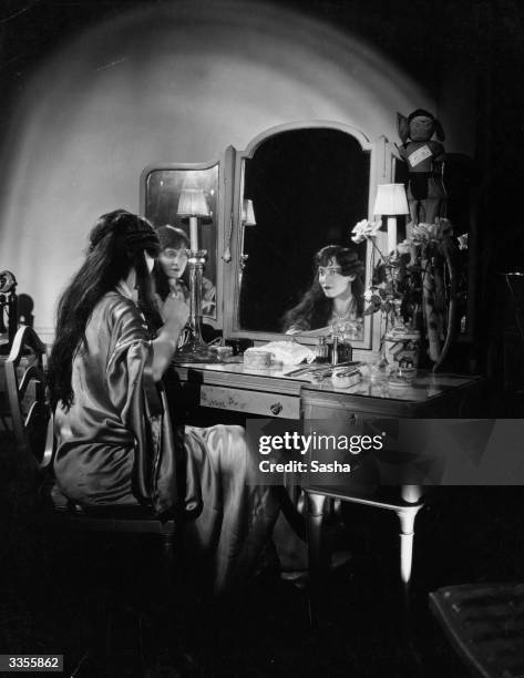 American dancer Adele Astaire , dancing partner and sister of Fred Astaire, sitting at a dressing table in a silk dressing gown.