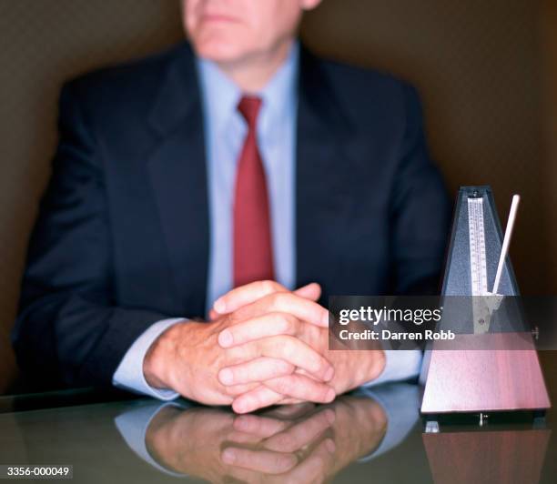 businessman near metronome - metronomo foto e immagini stock