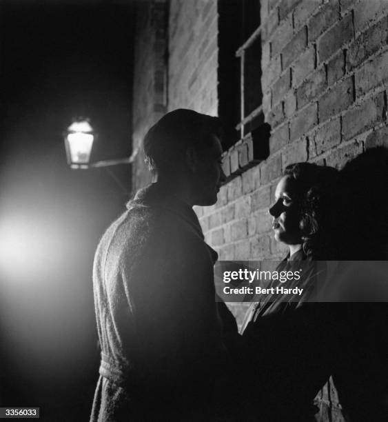 Teenager Betty Burden and her date standing together on a dimly-lit street in Birmingham. Original Publication: Picture Post - 5181 - Millions Like...