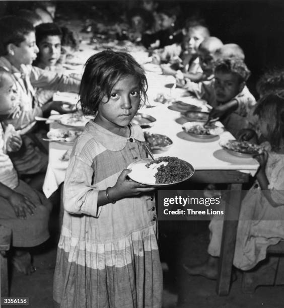 Palestine girl receiving food at a refugee camp run by the United Nations Relief And Works Agency in East Jordan.