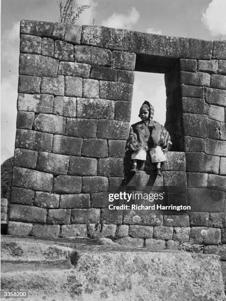 Child sitting in the trapezoid window of a ruined Inca house.