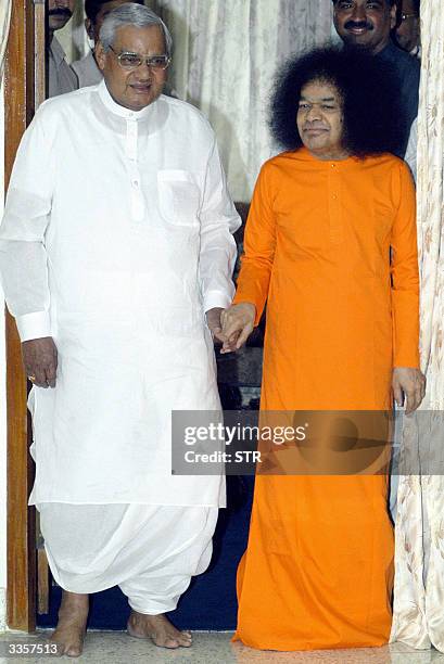 Indian Prime Minister Atal Behari Vajpayee walks out with Hindu holy man Satya Sai Baba after their meeting in Bangalore, 14 April 2004. Vajpayee who...