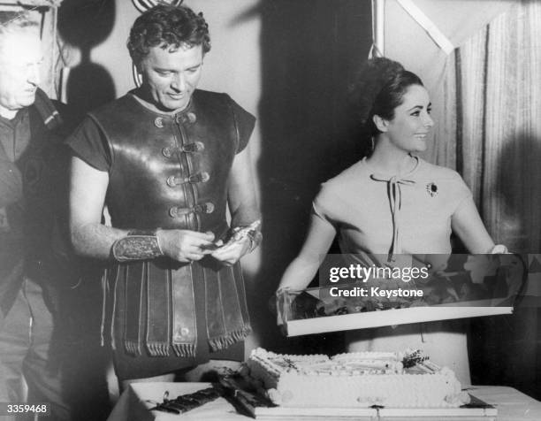 At Pinewood studios film star Elizabeth Taylor with a bouquet of roses and a cake presented to her on the occasion of her 31st birthday. Looking on...