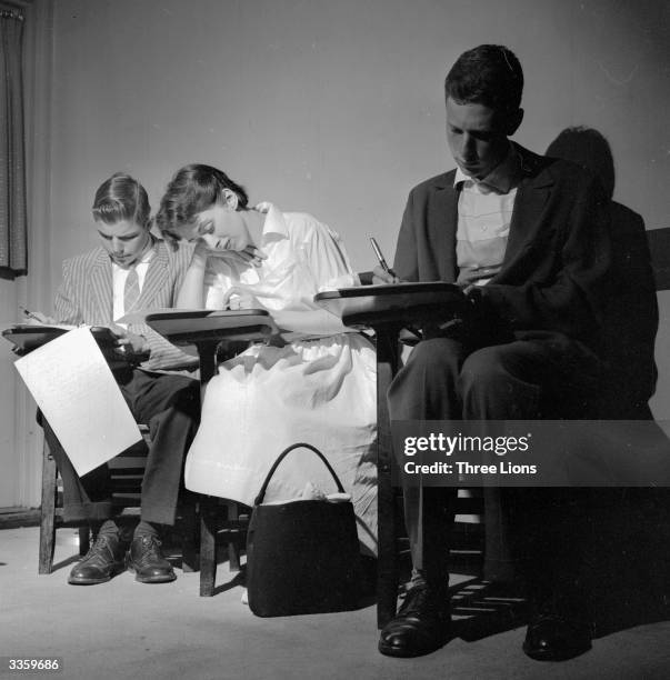 American mature students stuggling to complete examination papers whilst working from in desk chairs