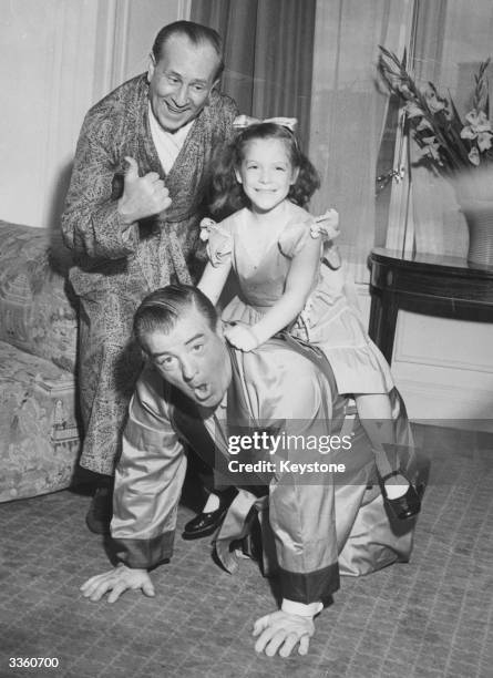 American comedy duo Bud Abbott smiling as Lou Costello gives his daughter Christie a piggy back ride. The pair starred in over 35 films together.