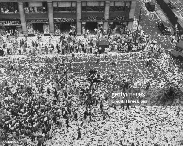 People celebrating on a American street strewn with paper on VJ day.