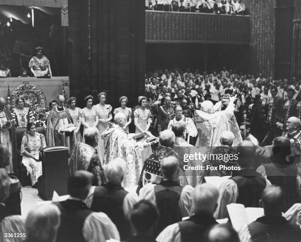 King George VI having St Edward's Crown placed on his head by the Archbishop of Canterbury at Westminster Abbey during his Coronation ceremony whilst...