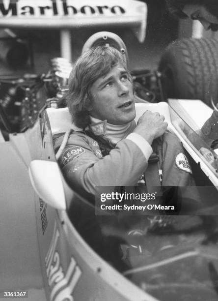 British racing driver James Hunt sitting inside a Formula 1 racing car before a race.