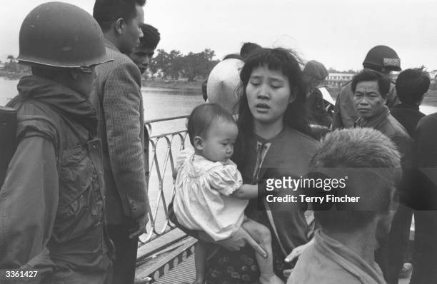 Vietnamese refugee crossing the 'Perfume River' with her baby with other refugees during the Vietnamese War.