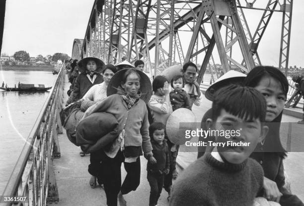 Group of Vietnamese refugees crossing a bridge over the Perfume River.