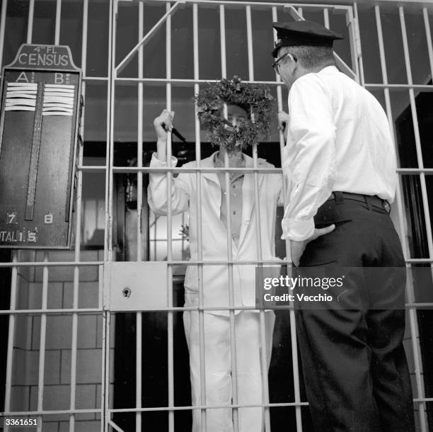 Prisoner talking to a guard through a Christmas wreath at the entrance to a cell block at Rikers Island penitentiary.