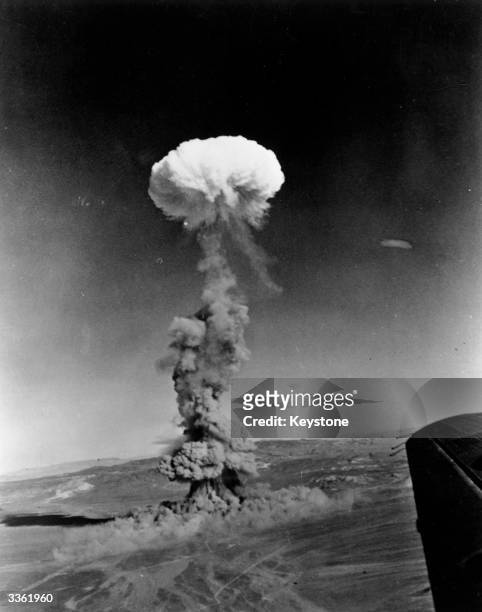 Mushroom cloud rising from the Nevada desert following an atomic test detonation. This photograph was made from a U.S. Air Force aircraft assigned to...