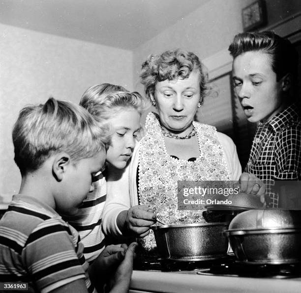 Television stars Ken, Ronnie and Glenn Walken watch as their mother Rosalie prepares supper at their home in Bayside, Long Island.