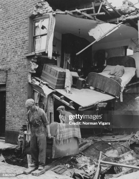 Workmen carry out salvaged furniture from a house in Bow, East London, after it was flooded by a burst water main.