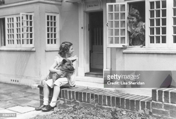 Princess Margaret and her sister Queen Elizabeth II in front of miniature cottage Y Bwthyn Bach in the grounds of Royal Lodge, Windsor, with two of...