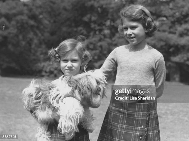 Queen Elizabeth II and her younger sister Princess Margaret in the grounds of the Royal Lodge, Windsor. Princess Margaret is holding one of their pet...