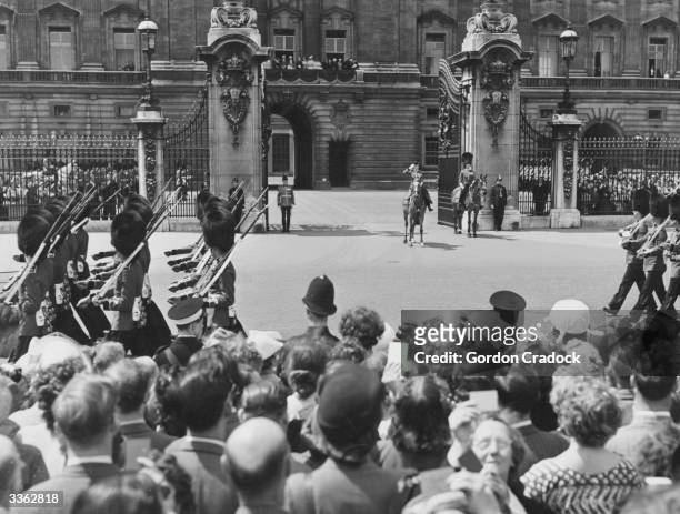 Crowds watch Queen Elizabeth II salute the Horseguards marching by in front of Buckingham Palace, London, after the Trooping of the Colour ceremony.
