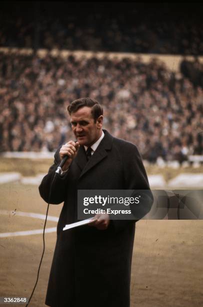 Leeds United football manager Don Revie speaking into a microphone before the start of a match.