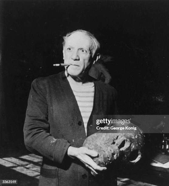 Spanish artist Pablo Picasso holding a piece of sculpture.