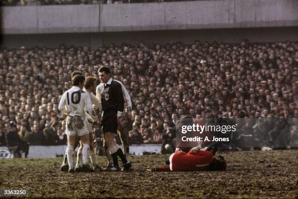 Referee Jack Taylor talks to Leeds United's Billy Bremner as Manchester United's Pat Crerand attends to injured team mate George Best.