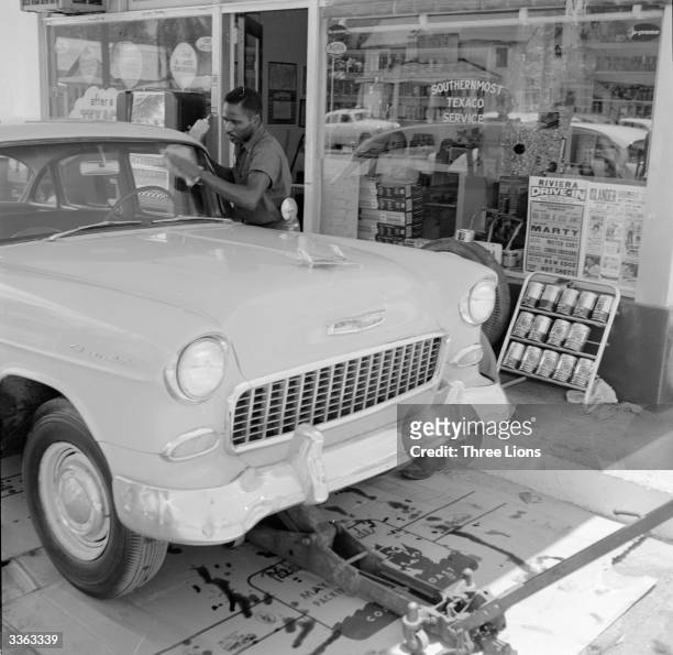 Man cleaning a car's windscreen at a gas station on Duval Street and Truman Avenue , Key West, Florida.