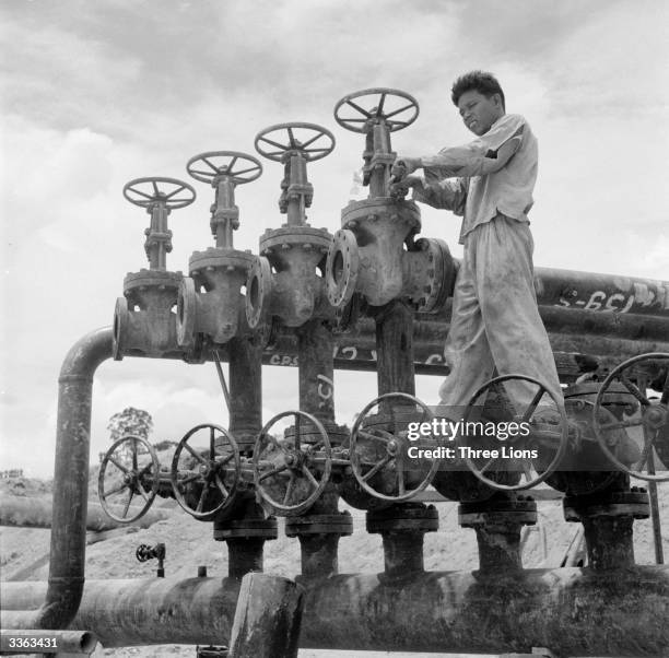 An oil worker operating the master valves which control pipe lines at an oil refinery on Sumatra, Indonesia.