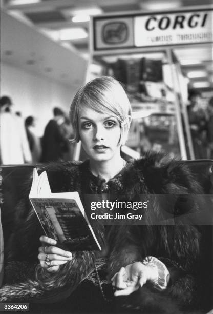 British model Twiggy reading a guide book to Tokyo at London Airport before departing for Japan, where she will be modelling a fashion collection.