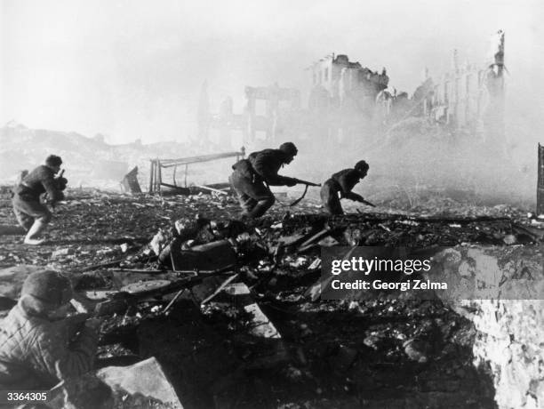 Red Army troops storming an apartment block amidst the ruins of war-torn Stalingrad during World War II.