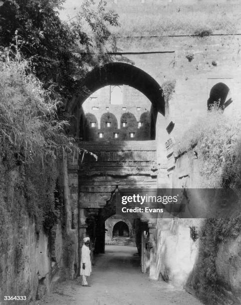 An Indian man stands at the gateway to the fort of Uparkot at Junagadh, India. The gateway is considered a fine piece of Hindu architecture.