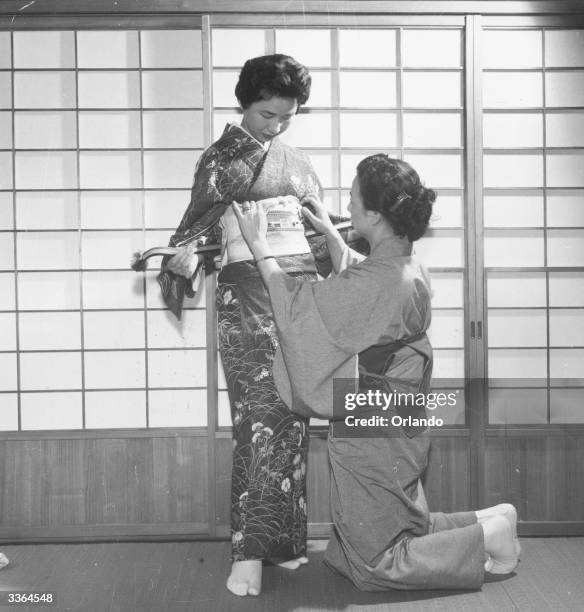 Woman fixing another woman's obi. Obis are about two feet wide, folded double and about eleven feet long.