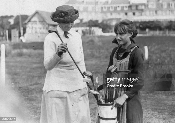 Caddy holds the bag as Mrs Vanderbeck choosing her club at the French Ladies Golf Championship at Le Touquet.