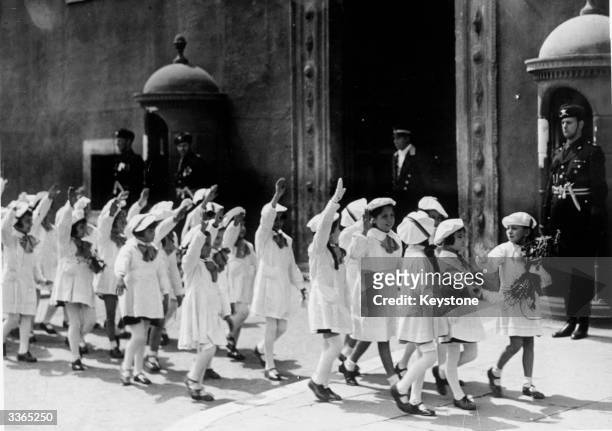 Young girls from Rome's elementary schools give the fascist salute as they pass the Palazzo Venezia. The palace is the home of 'Il Duce', the fascist...
