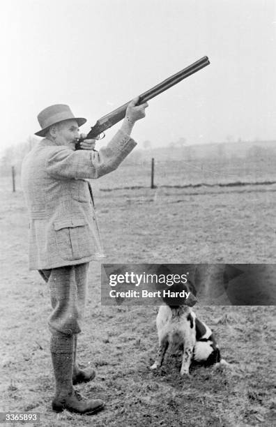 Trainer takes aim at a pheasant while his gun dog sits calmly by his side. Original Publication: Picture Post - 4480 - Training Gun Dogs - pub. 1948