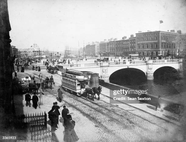 Trams making their way along the banks of the River Liffey in Dublin, with the O'Connell Bridge in the background.