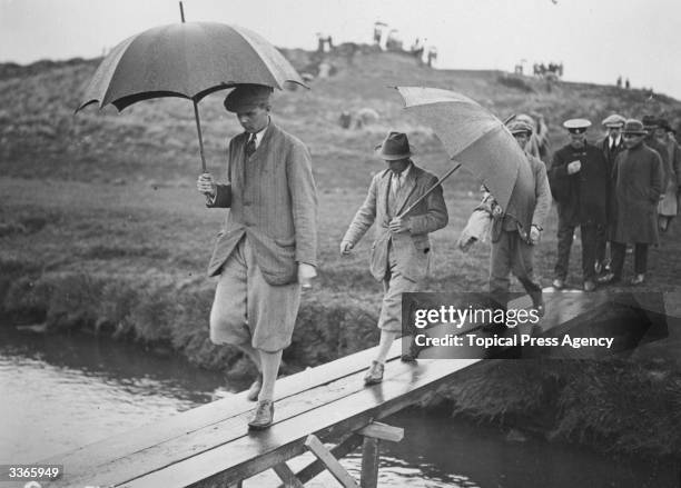 British golfer Roger Wethered leading a group of competitors across a brook during a rainy round of the Amateur Golf Championships at Prestwick golf...