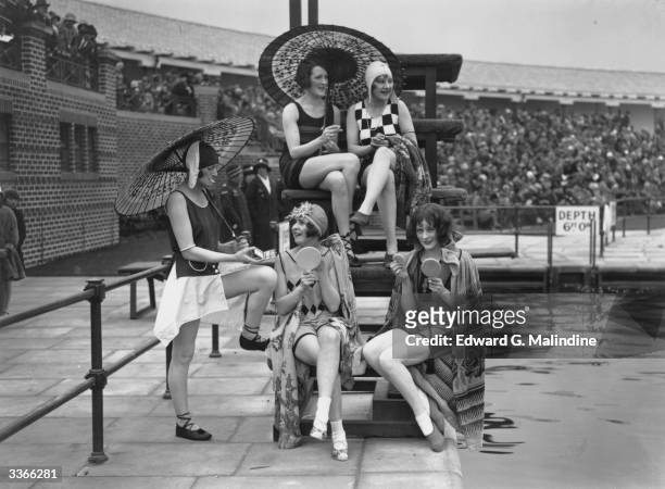 Group of young women wearing the latest in bathing fashions put on their make-up beside a pool at a Southport holiday camp, Merseyside.
