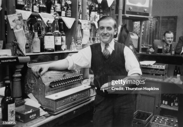 Bartender and a cash till behind the bar of a Liverpool public house. Original Publication: Picture Post - 8995 - Liverpool Slums - unpub.