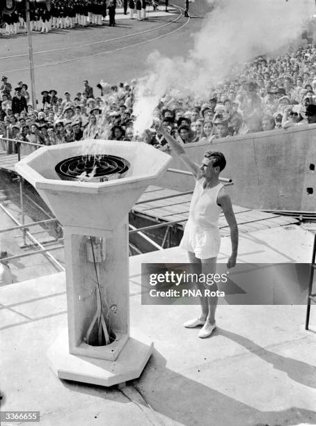 British athlete bears the Olympic Torch into the Empire Stadium at Wembley, London, and inaugurates the 1948 Olympic Games by lighting the ceremonial...