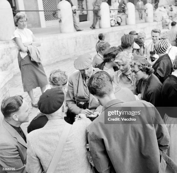 Group of tourists sorting out coins to throw into the 18th century Trevi fountain in Rome.