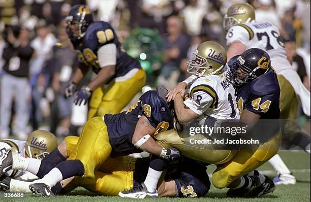 Quarterback Cade McNown of the UCLA Bruins is tackled by Albert Dorsey and Nate Geldermann of the Cal Golden Bears during a game at the Memorial...