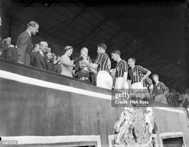 Queen Elizabeth II, accompanied by Prince Philip, presents the FA Cup trophy to Manchester City captain Roy Paul, after their 3-1 win over Birmingham...