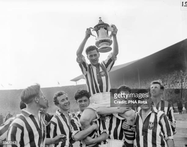 West Bromwich Albion captain, Len Millard, holds the FA Cup aloft, while his team mates carry him around Wembley Stadium, on a lap of honour. West...